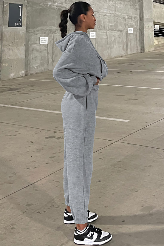 Set of plain gray sports clothes with hooded sweatshirt and jogging pants with falling shoulders