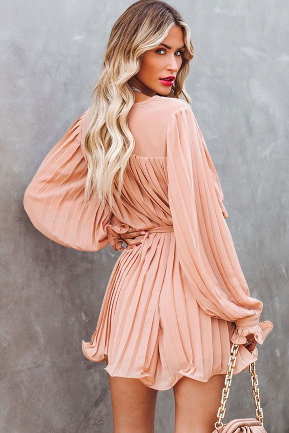 Pink pleated romper with ruffles and buttons at the waist, V-neck