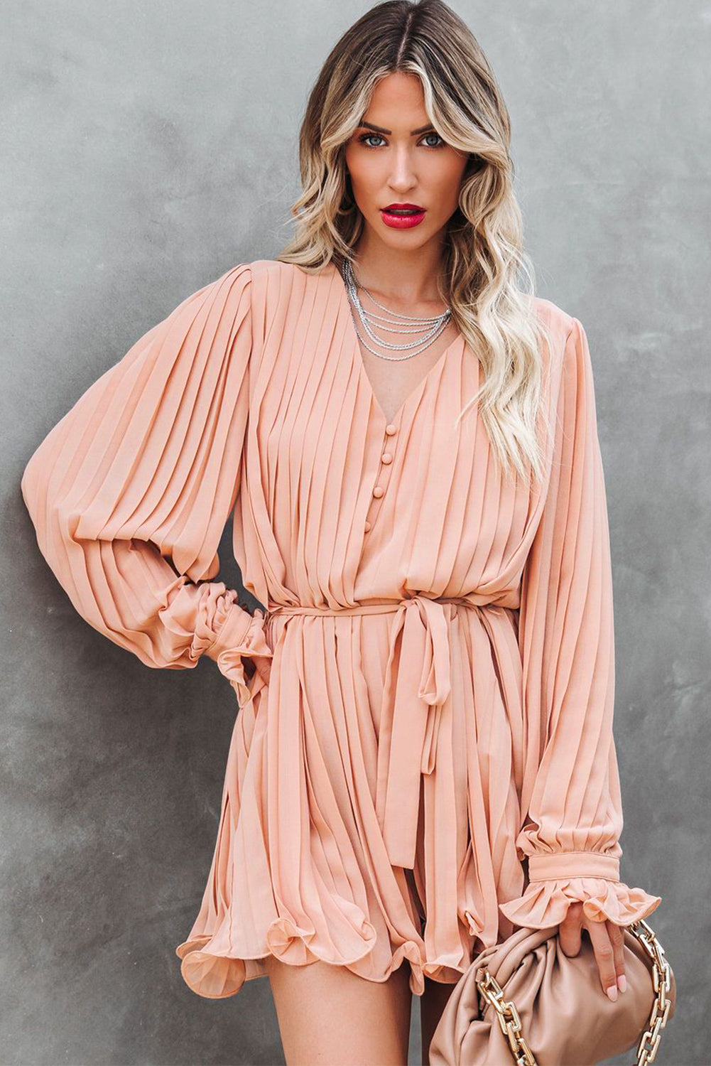 Pink pleated romper with ruffles and buttons at the waist, V-neck