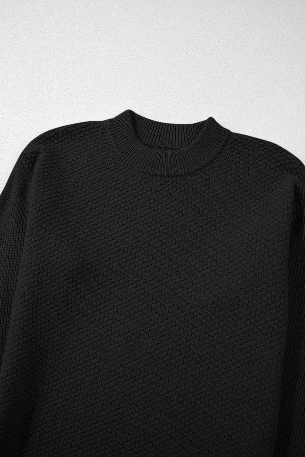 Pull ample noir en tricot texturé uni, manchette fendue, épaules tombantes