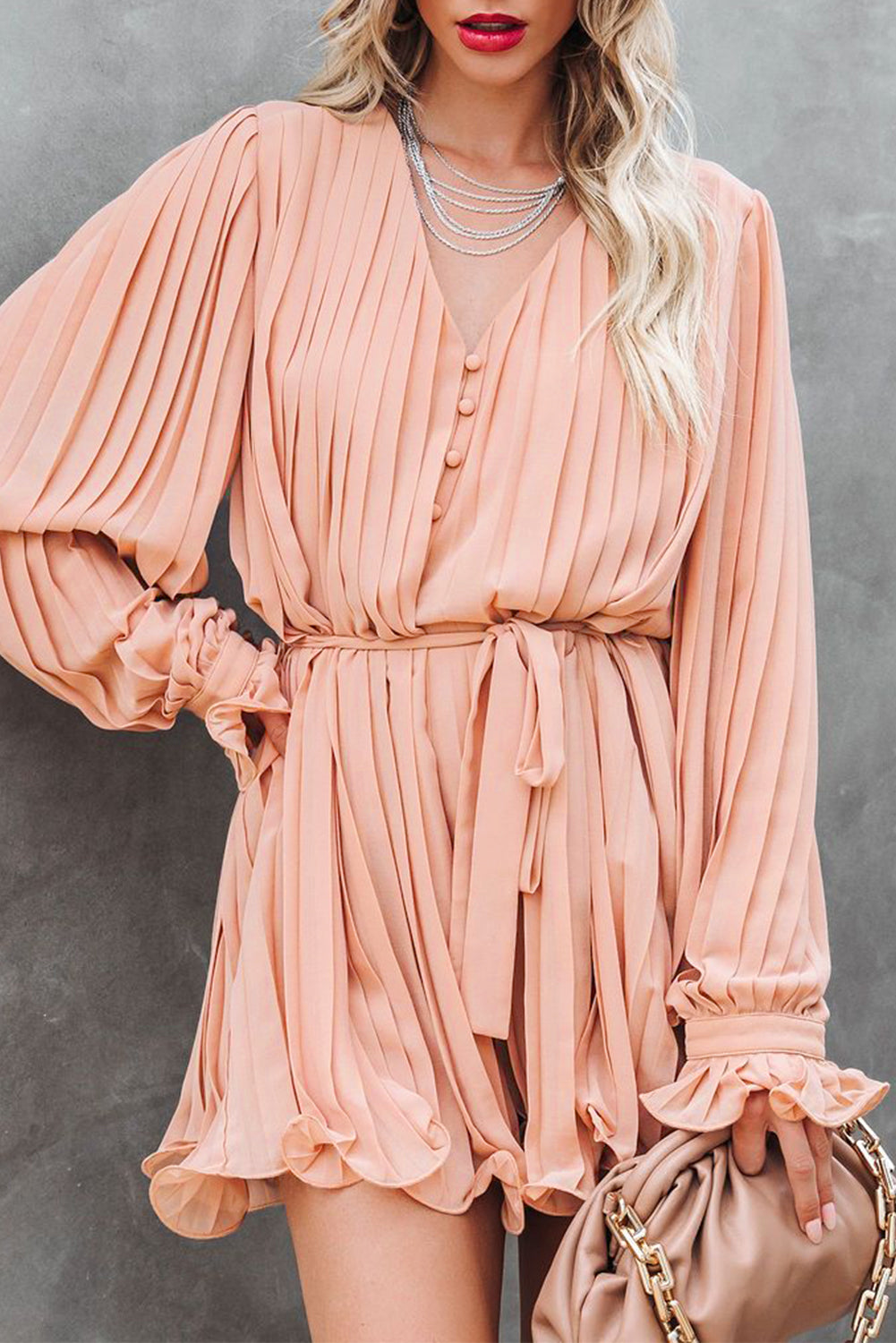 Pink pleated romper with ruffles and buttons at the waist, V-neck