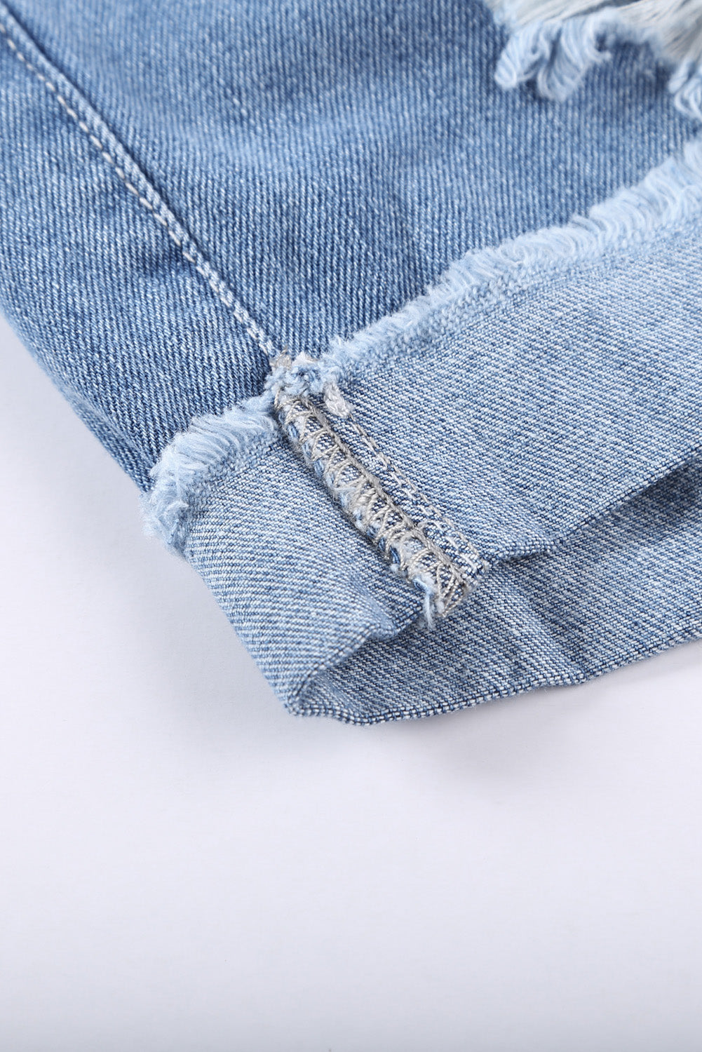 Pantaloncini di denim blu arrotolato strappato in difficoltà