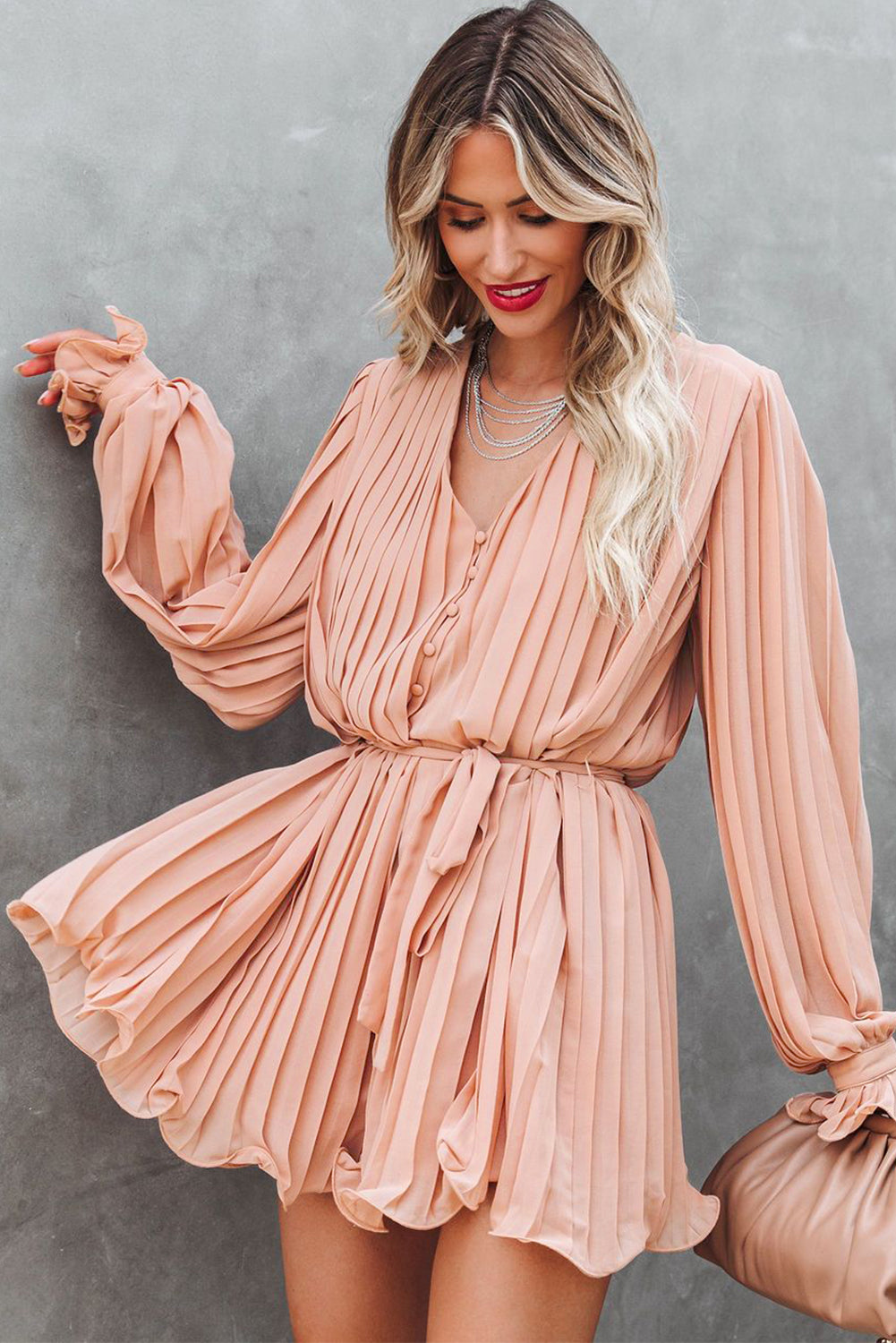 Pink pleated romper with ruffles and buttons at the waist, V-neck