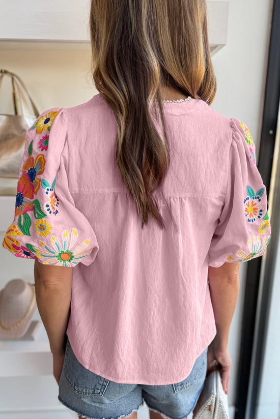 Blusa rosa con flores bordadas y mangas hinchadas, cuello dividido