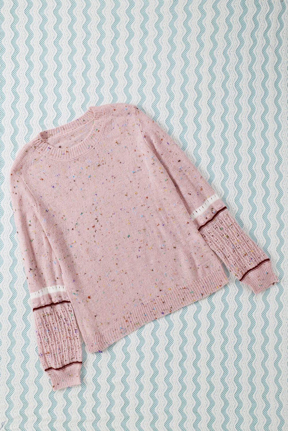 Pink sweater with patterned sleeves and pilled details