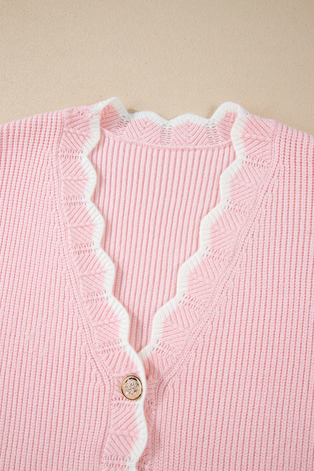 Pink ribbed knit button-up cardigan with side pockets and scalloped edges