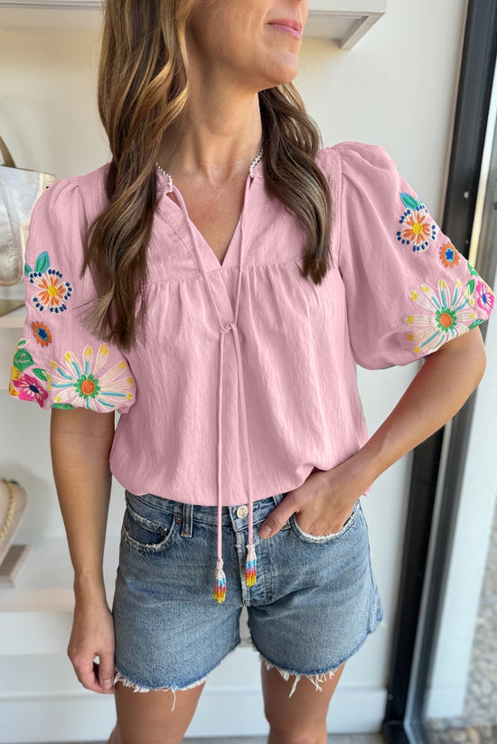 Blusa rosa con flores bordadas y mangas hinchadas, cuello dividido