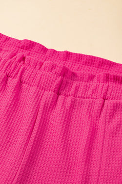 Large pink textured shorts with rolled edges and ruffles, elastic waist