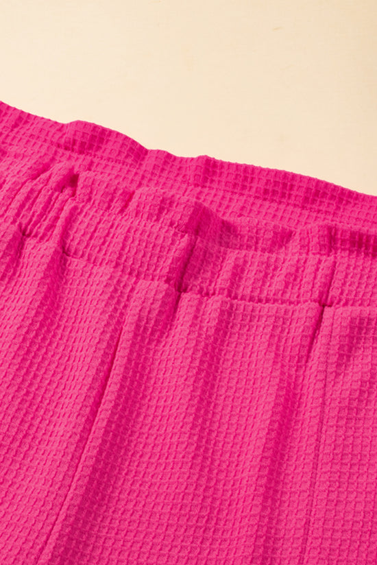 Grandes pantalones cortos de textura rosa con bordes y volantes enrollados, cintura elástica