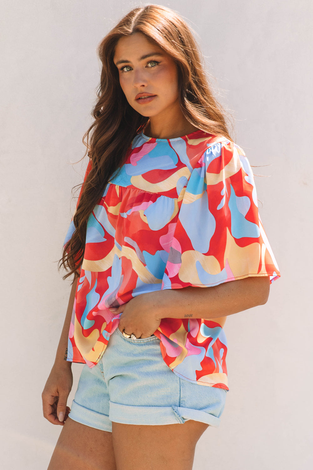 Blusa multicolor con cuello y mangas anchas con un patrón abstracto