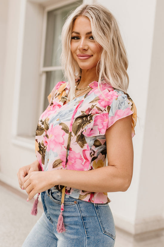 Pink blouse with short sleeves and floral print with pompom and tie